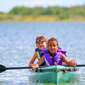 Two children paddle a green kayak on a lake at Redberry Lake Regional Park.